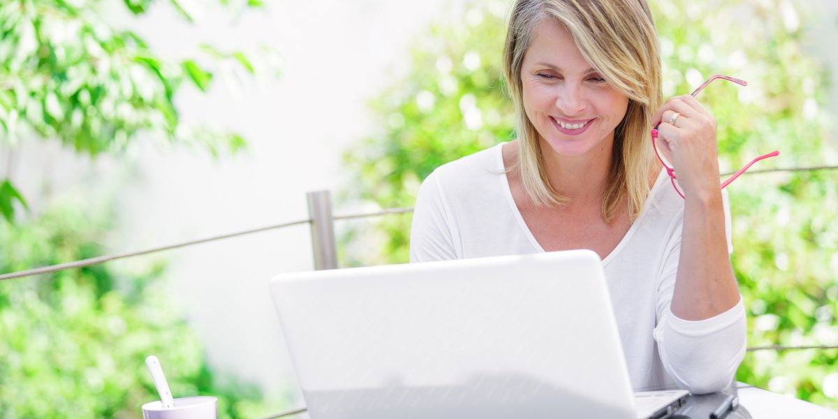 beautiful woman working on a computer at home with green garden on her background